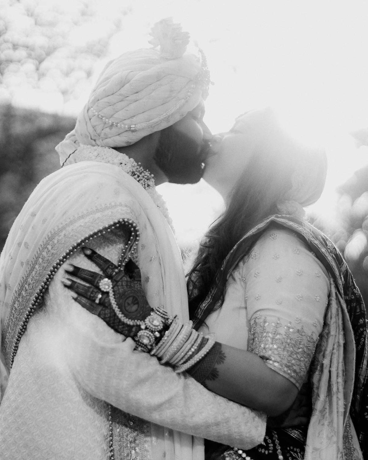 Groom kisses bride on stage after jaimala ceremony – captured by candid wedding photographers in India