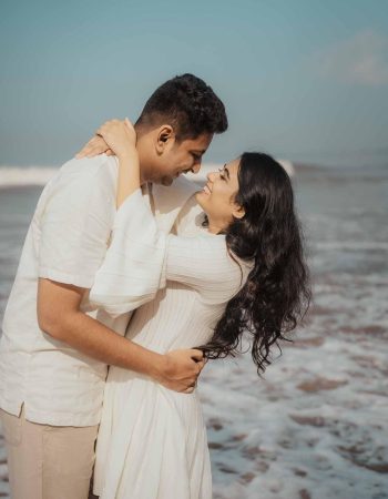 A couple posing during a pre-wedding photoshoot on Goa beach with a golden sunset in the background.